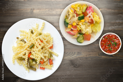 pasta with green beans with garlicand carrots on a white plate on a wooden background. Mediterranean Kitchen . photo