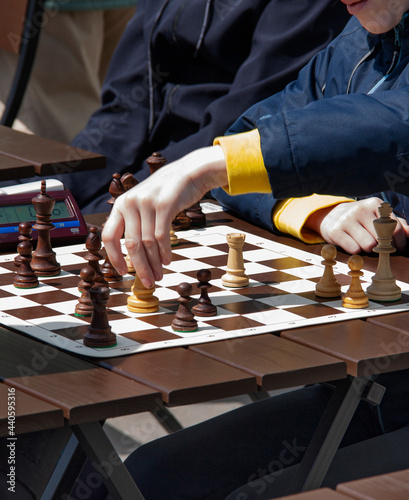 Close up of hands of Boy playing quick chess on the street with timer. Chess street tournament.