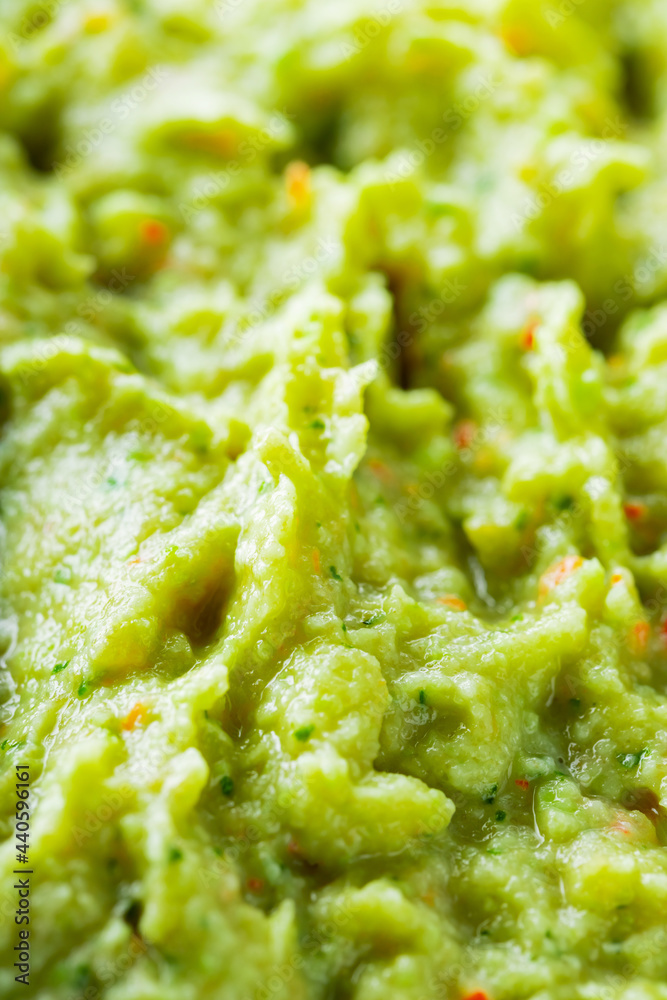 Guacamole close-up. Avocado guacamole sauce with fresh ingredients. Food background of guacamole sauce