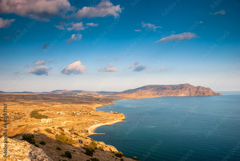 Sudak, Crimea - a view from Cape Meganom. A ridge of the Crimean mountains against the background of a blue sky with beautiful clouds.