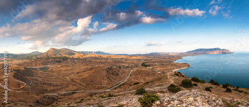 Sudak, Crimea - a view from Cape Meganom. A ridge of the Crimean mountains against the background of a blue sky with beautiful clouds.