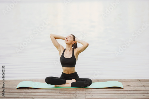 Woman practicing advanced yoga by the water