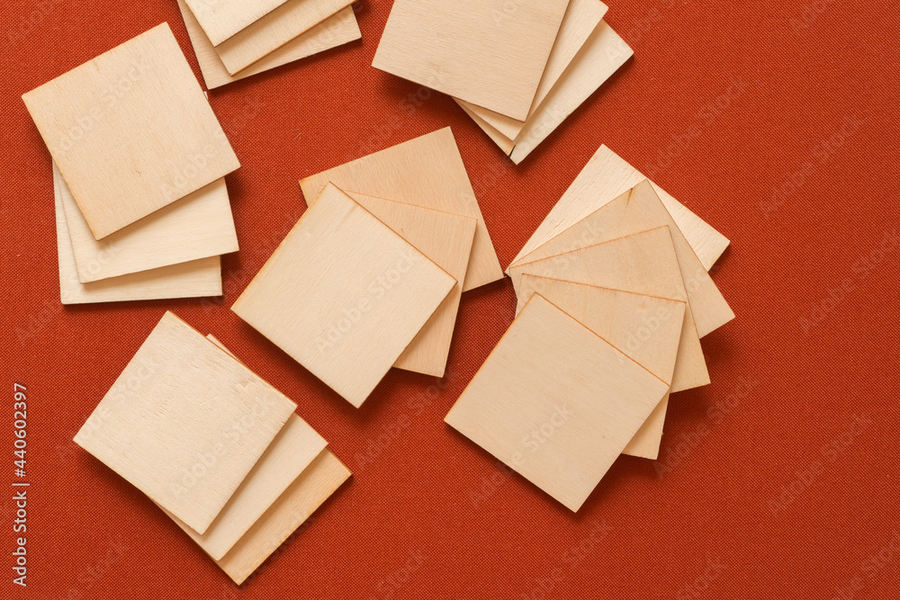 laser cut thin untreated or natural plywood squares on red brown or terracotta fabric background - photographed from above in a flat lay style, with ambient light - sun set color palette laser cut thin untreated or natural plywood squares on red brown or terracotta fabric background - photographed from above in a flat lay style, with ambient light - sun set color palette