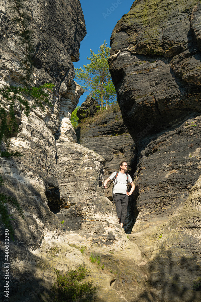 Obraz premium Adult male tourist looking around and enjoying surroundings at sandstone rock formations in Tisá, Czech republic. Film location of The Chronicles of Narnia