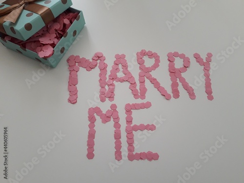 Little gift box with a marriage proposal written in pink confetti