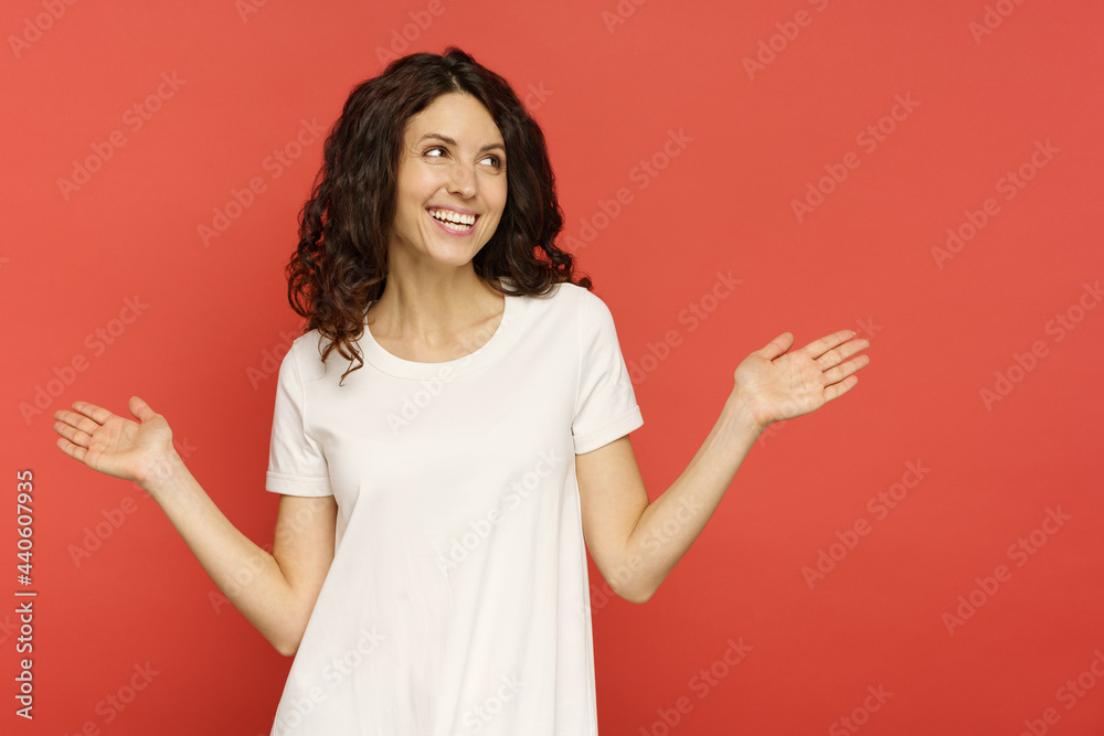 Cheering happy woman with raised hands and open palms celebrate success, carefree surprised winner girl look aside to copy space. Cute female with cheerful smile isolated over red studio background Cheering happy woman with raised hands and open palms celebrate success, carefree surprised winner girl look aside to copy space. Cute female with cheerful smile isolated over red studio background