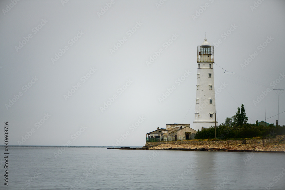 White lighthouse on the coast of Crimea on an overcast rainy day