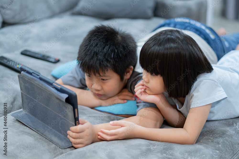two chinese children addicted tablet, asian child watching telephone together on their bed, kid using smartphone two chinese children addicted tablet, asian child watching telephone together on their bed, kid using smartphone