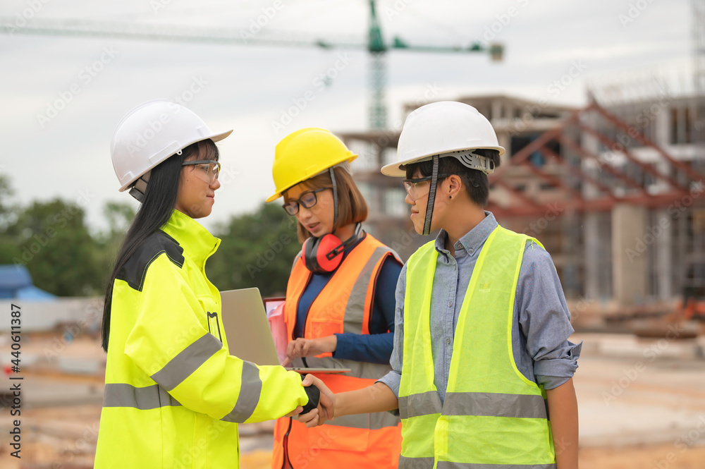 Young and senior Engineers discuss about work of large building underconstruction,Three people working on site of under construction
