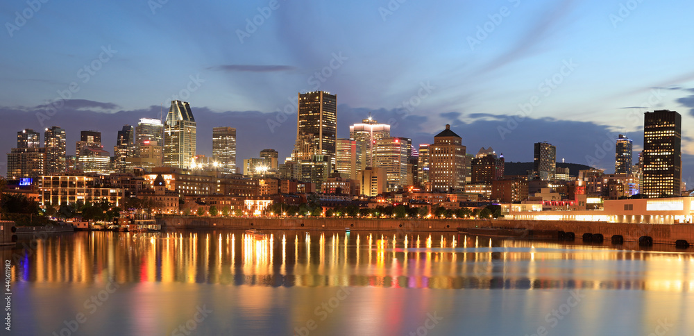 Naklejka premium Montreal skyline at dusk with lights reflections on St Lawrence River in Quebec, Canada