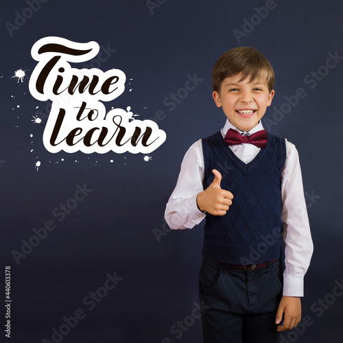 Close-up of a smiling, laughing, happy, funny teenage boy showing thumb up isolated on blue background. lettering Time to learn