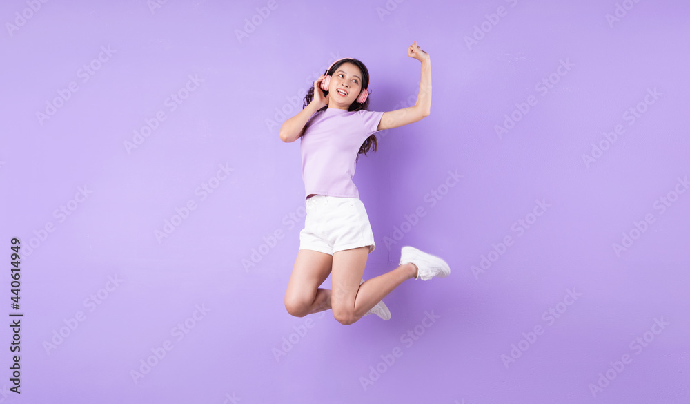 Young asian girl jumping up on purple background