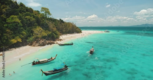Aerial tropical island beach boat tour. Turquoise sea water. Traditional wooden long-tail boats, floating on vacation trip to paradise shore. Aamazing beautiful wild landscape in Thailand. Travel