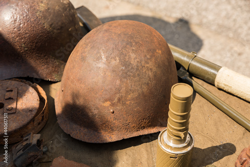 An old rusty WWII army helmet lies on a display table