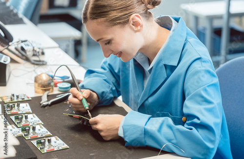 Worker in electronics manufacturing soldering a component for the prototype series by hand