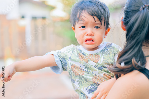 Portrait of 1 year 7 months baby boy crying with mother while she holds him and tries to comfort him.