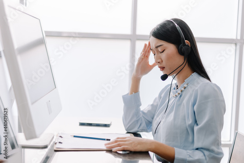 Call center operators provide advice and counseling to help clients with stressful gestures, operators are having a headache and use their hands to touch their heads with a tired expression.