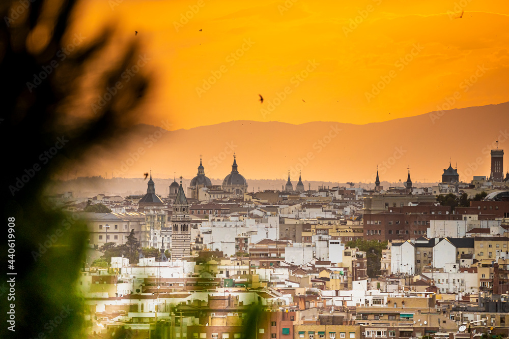 Puesta de sol en la ciudad de Madrid con vistas a los edificios y pequeñas nubes con el horizonte anaranjado, atardecer.
