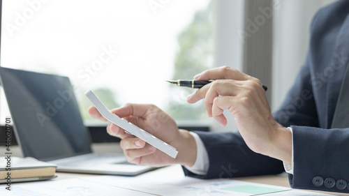 Businessman presses a calculator to calculate earnings and analyze company earnings in his private office, Information in finance and accounting, Company performance and revenue.