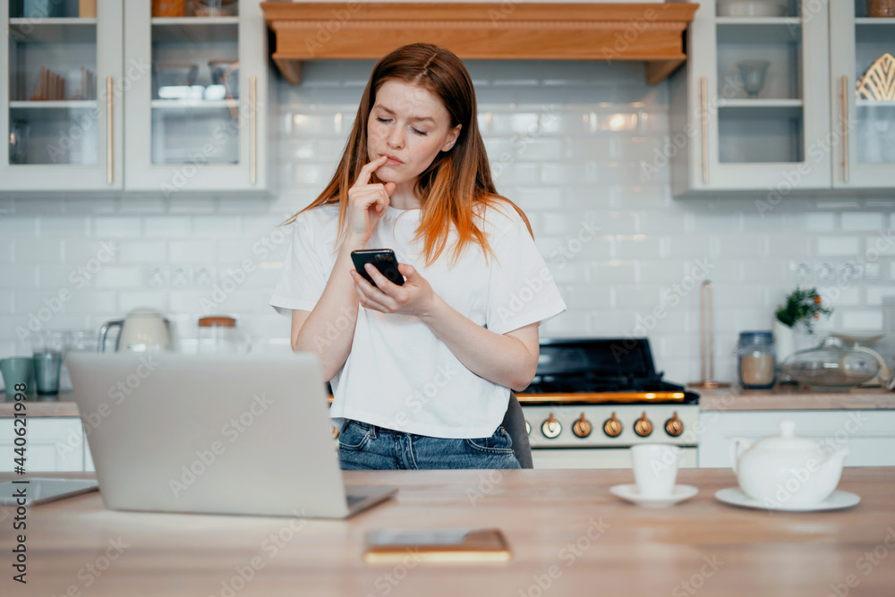A female blogger is surfing the Internet on a laptop. The housewife keeps a record of expenses in the table online at home. Student beautiful girl study at home remotely. A female blogger is surfing the Internet on a laptop. The housewife keeps a record of expenses in the table online at home. Student beautiful girl study at home remotely.