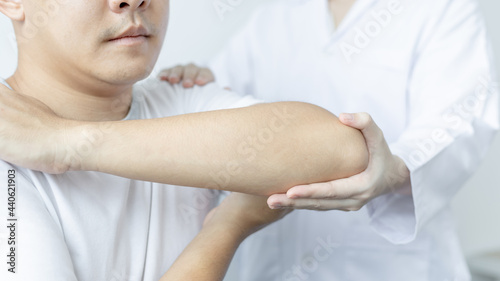 Physical therapy, Female physiotherapist treats arms and shoulders pain for a male patient attending in clinic, Bone arrangement, Non-surgical medical treatment, Modern medical techniques.