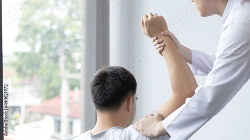 Physical therapy, Female physiotherapist treats arms and shoulders pain for a male patient attending in clinic, Bone arrangement, Non-surgical medical treatment, Modern medical techniques.