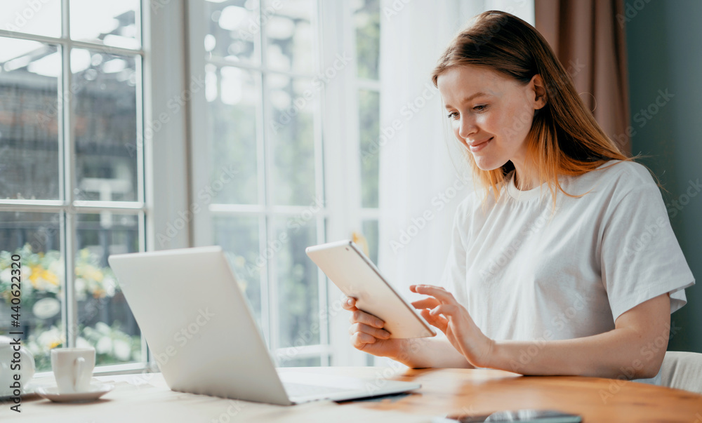 The housewife keeps a record of expenses in the table online at home. Student beautiful girl study at home remotely. A female blogger types text on a laptop.