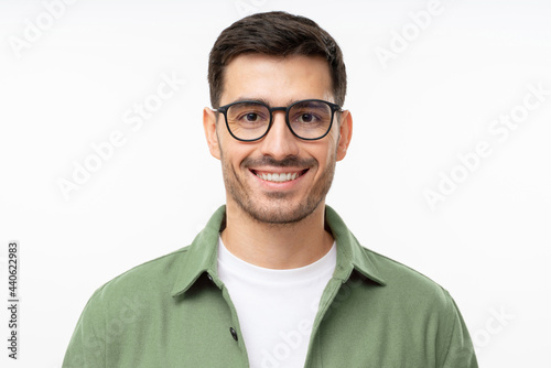 Headshot portrait of young handsome smiling man in green shirt and glasses, isolated on gray background © Damir Khabirov