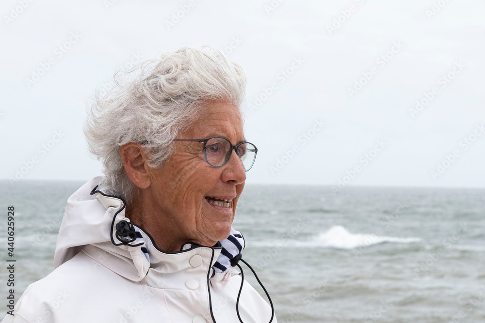 An elderly woman walks on a beach in Brittany, France An elderly woman walks on a beach in Brittany, France