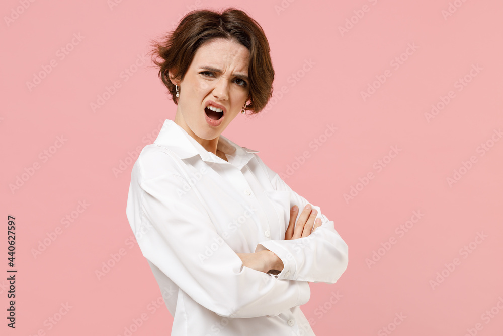 Side view young indignant sad shrewd employee business woman corporate lawyer in classic formal white shirt work in office hold hands crossed isolated on pastel pink color background studio portrait. Side view young indignant sad shrewd employee business woman corporate lawyer in classic formal white shirt work in office hold hands crossed isolated on pastel pink color background studio portrait.