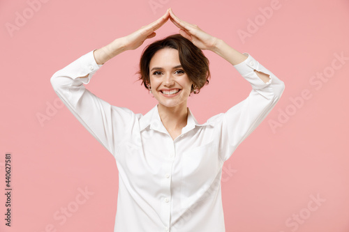 Young successful employee business woman corporate lawyer in classic formal white shirt work in office hold folded hands above head like house roof stay home isolated on pastel pink color background.