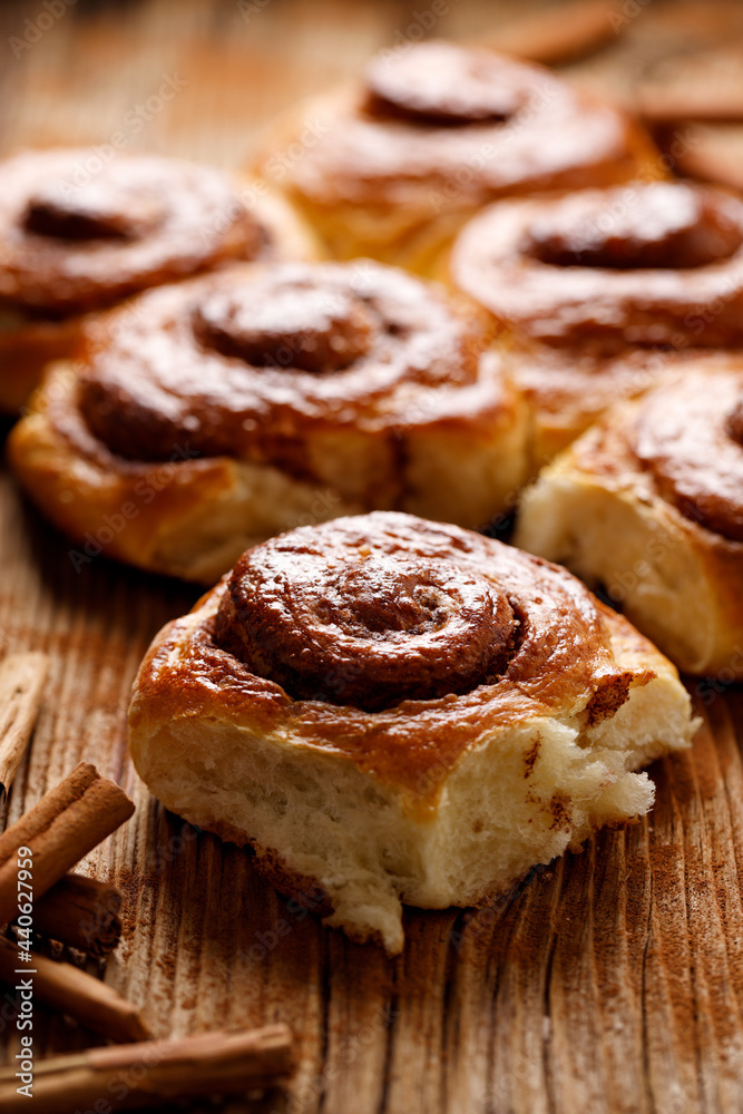 Homemade spiral-shaped sweet cinnamon buns, focus on the first bun, close up view. Traditional danish pastry.