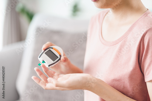 Asian woman checking blood sugar level by Digital Glucose meter, Healthcare and Medical, diabetes, glycemia concept