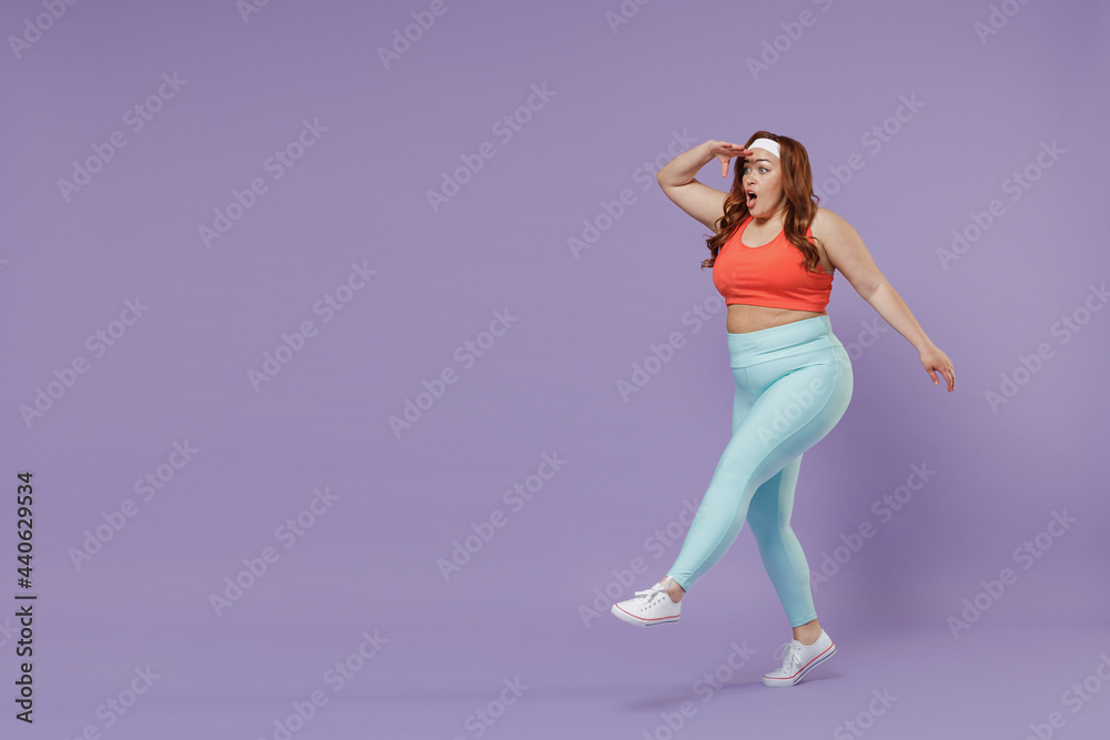 Full length young chubby overweight plus size big fat fit woman in top warm up training hold hand forehead look far away distance go isolated on purple background gym Workout sport motivation concept