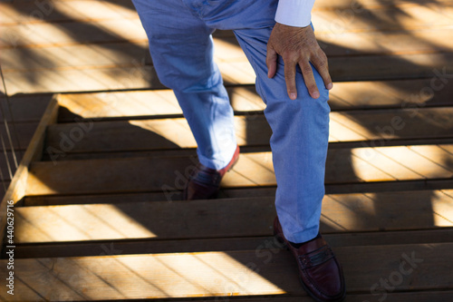 Senior adult having knee pain while climbing up stairs