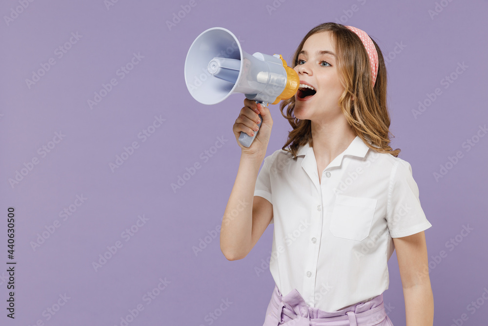 Little expressive promoter kid girl 12-13 years old in white shirt scream in megaphone hot news about sale discount isolated on purple background children studio portrait. Childhood lifestyle concept Little expressive promoter kid girl 12-13 years old in white shirt scream in megaphone hot news about sale discount isolated on purple background children studio portrait. Childhood lifestyle concept