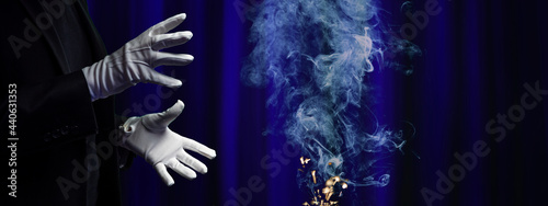 Magician with white gloves on stage with a poof of smoke and sparks.  Presto! photo