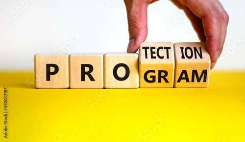 Protection program symbol. Businessman turns wooden cubes and changes the word 'program' to 'protection'. Beautiful yellow table, white background, copy space. Business, protection program concept.