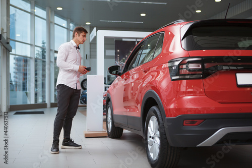 Full length shot of a businessman looking at new SUV car for sale at the dealership