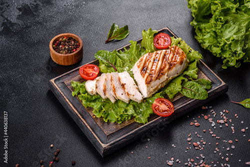 Pieces of chicken, tomatoes and lettuce leaves on a dark concrete background