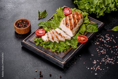 Pieces of chicken, tomatoes and lettuce leaves on a dark concrete background