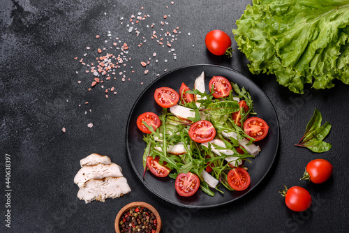 Pieces of chicken, tomatoes and lettuce leaves on a dark concrete background