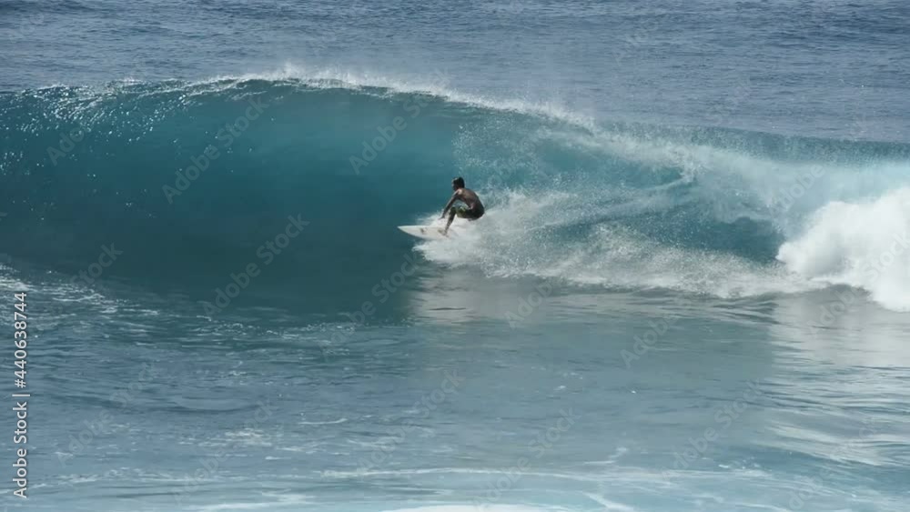 Surfing in Honolua Bay - A skillful surfer riding in and out and along the ridge of big blue breaking tidal waves in Honolua Bay at north-west coast of West Maui. Hawaii. USA. Surfing in Honolua Bay - A skillful surfer riding in and out and along the ridge of big blue breaking tidal waves in Honolua Bay at north-west coast of West Maui. Hawaii. USA.