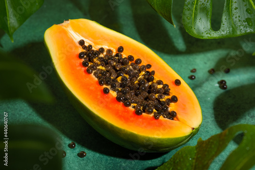 Fresh half of papaya with seeds on tropical leaves background. Tropical exotic fruit. photo