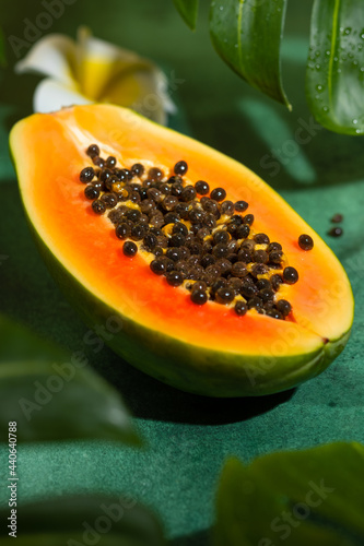 Fresh half of papaya with seeds on tropical leaves background. Tropical exotic fruit. photo