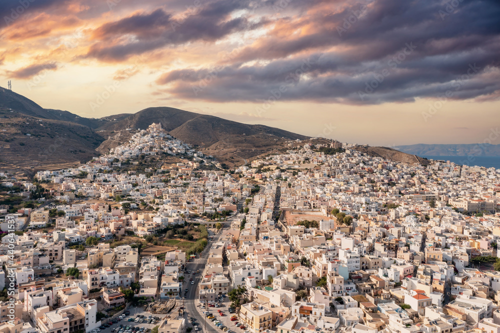 Syros island, Greece, aerial drone view. Ermoupolis and Ano Siros town cityscape, cloudy sky at sunset