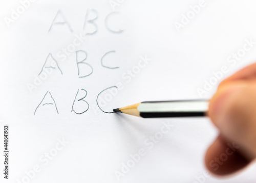 A person writing the alphabet with a pencil. Earning learning concept.