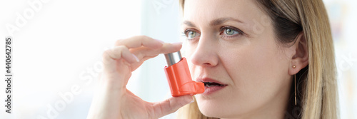 Sick woman holding hormone inhaler near mouth photo