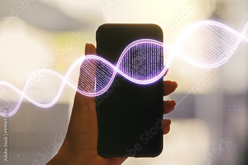 Double exposure of creative DNA hologram and hand with cell phone on background. Bio Engineering and DNA Research concept