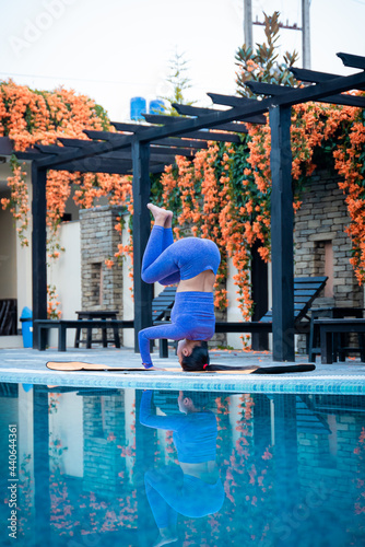 Tripod headstand yoga asana. Girl upside down pilates practice salamba sirasana, beautiful reflection on water
 photo